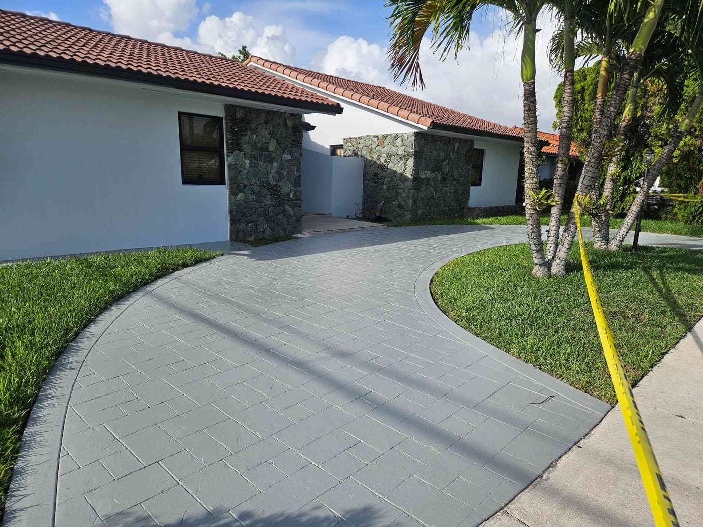 Single-story home with natural stone accent walls and a freshly resurfaced gray paver driveway