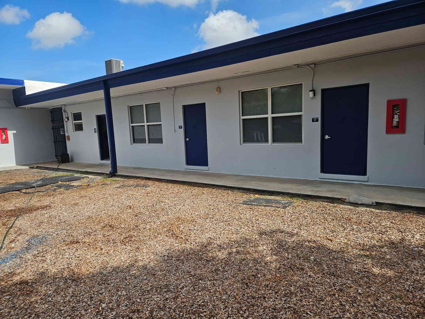 Repainted single-story school building with white walls, blue trim and matching blue doors