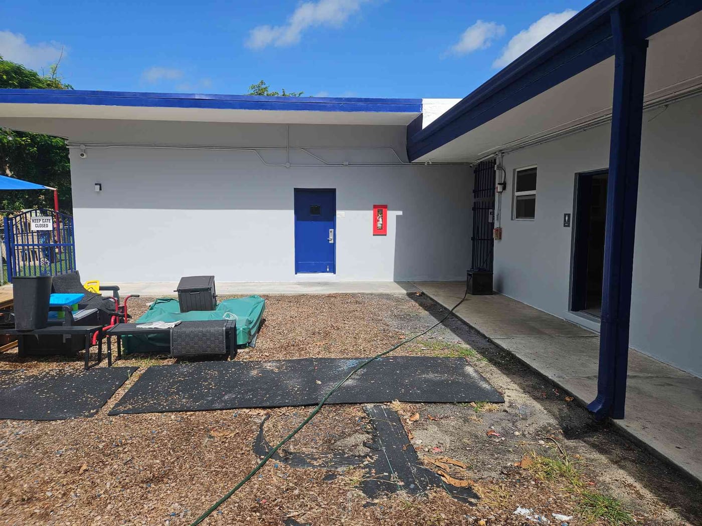 Freshly repainted school courtyard with white walls and a bright blue door