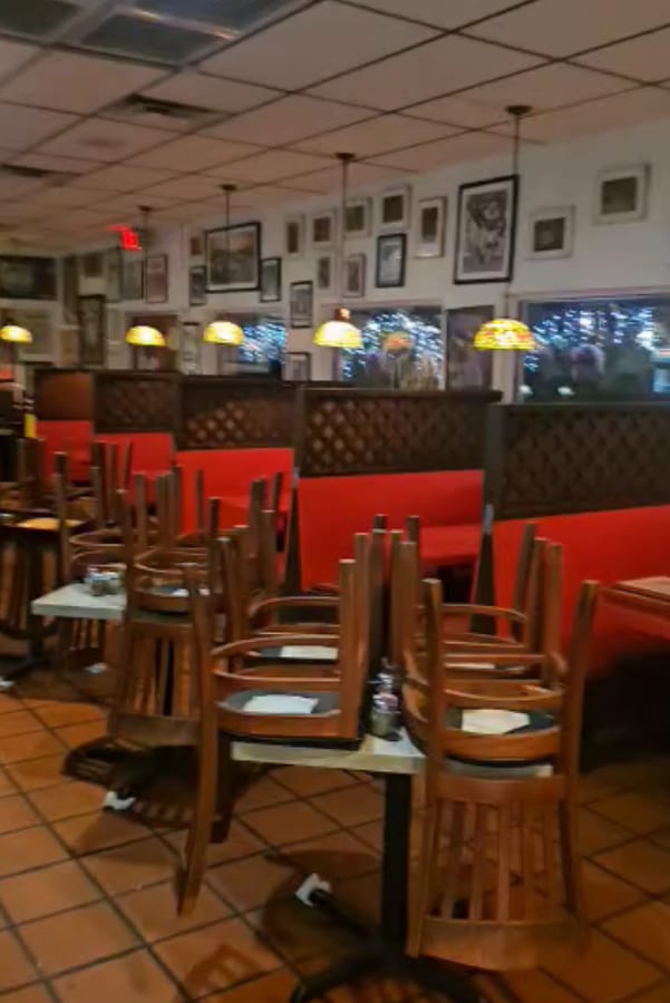 Restaurant interior with freshly painted white walls, red booths and stacked wooden chairs — a commercial painting project