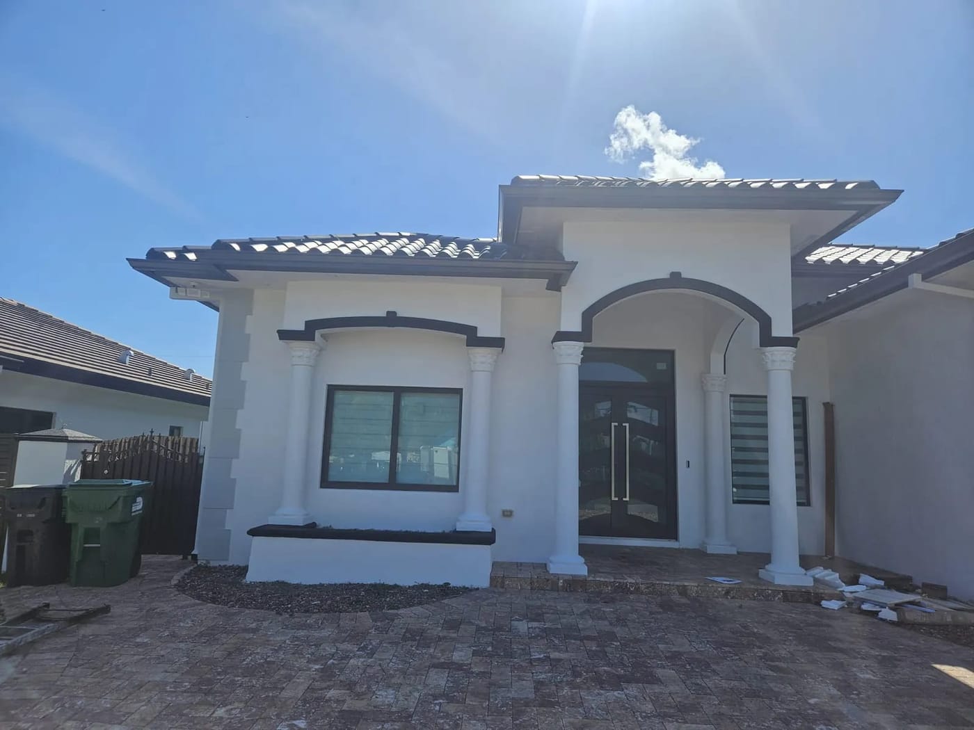 Newly painted white stucco home with charcoal trim and arched entry